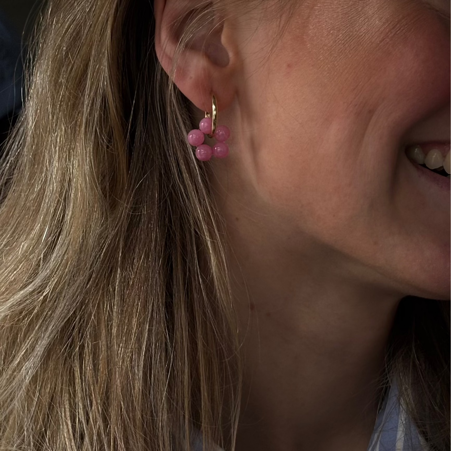 Tragebild von goldenen Kreolen mit pinker Perlenblume